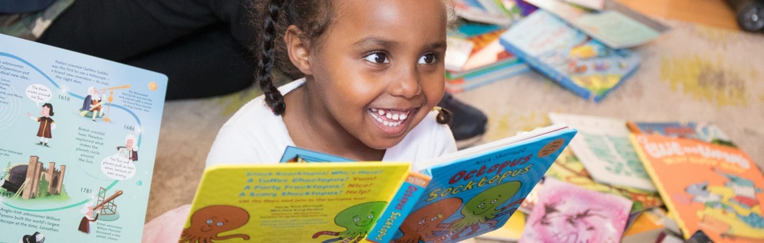 Little girl holding a book and smiling