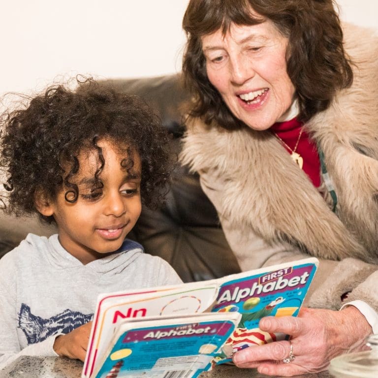 Older volunteer reading with little boy_Intergenerational Week